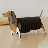 A wooden dachshund-shaped holder with dark felt coasters stacked as the dog’s body, placed on a light-colored table. Perfect for fans of Dachshund coasters and charming decor.