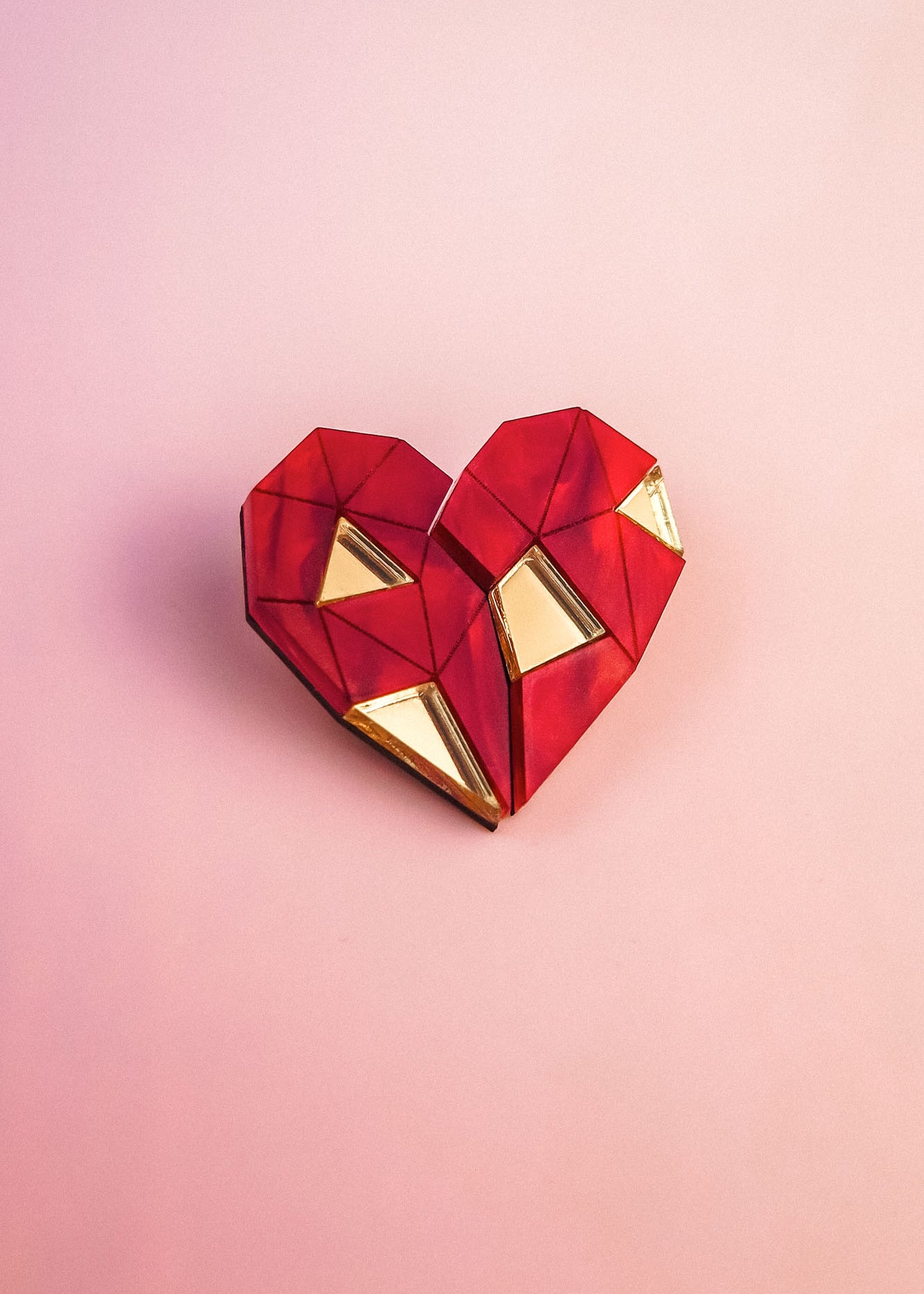 A geometric, origami-style red heart with gold triangular accents sits on a soft pink background—perfect as romantic gift or inspiration for handcrafted pins.